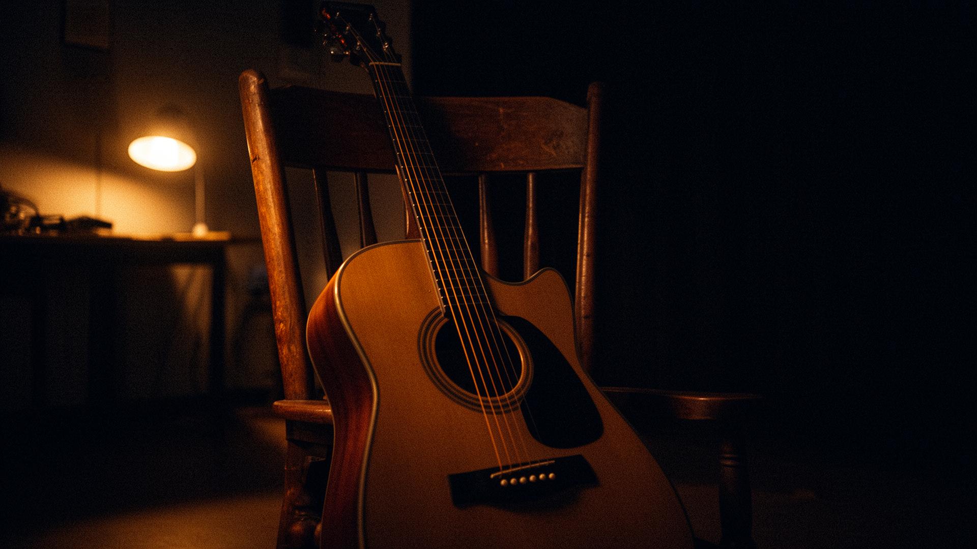Acoustic guitar lit by a single warm lamp in a songwriter's studio